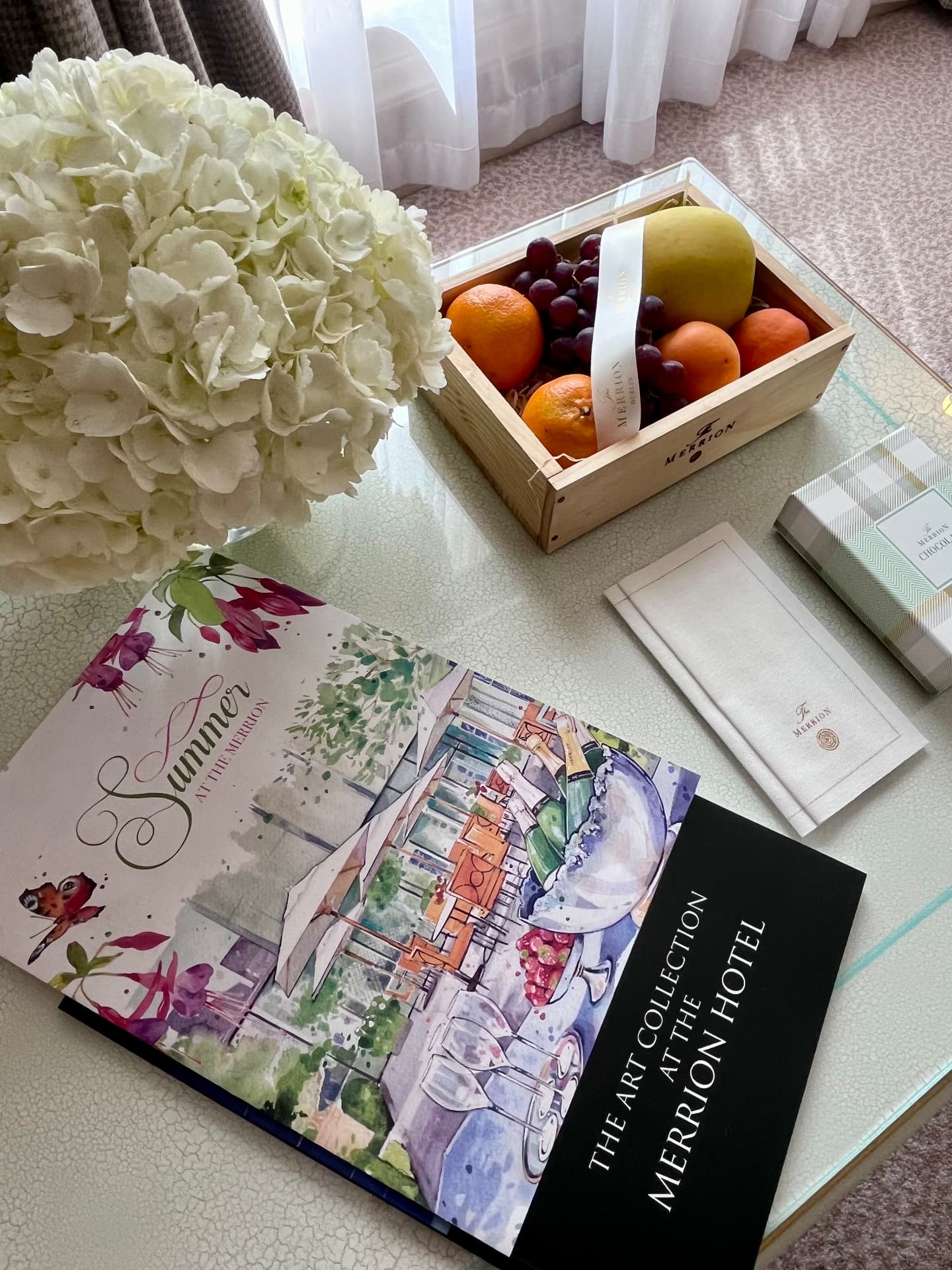 Hydrangeas, fruit, chocolates and The Merrion art collection guide on a guest-room table
