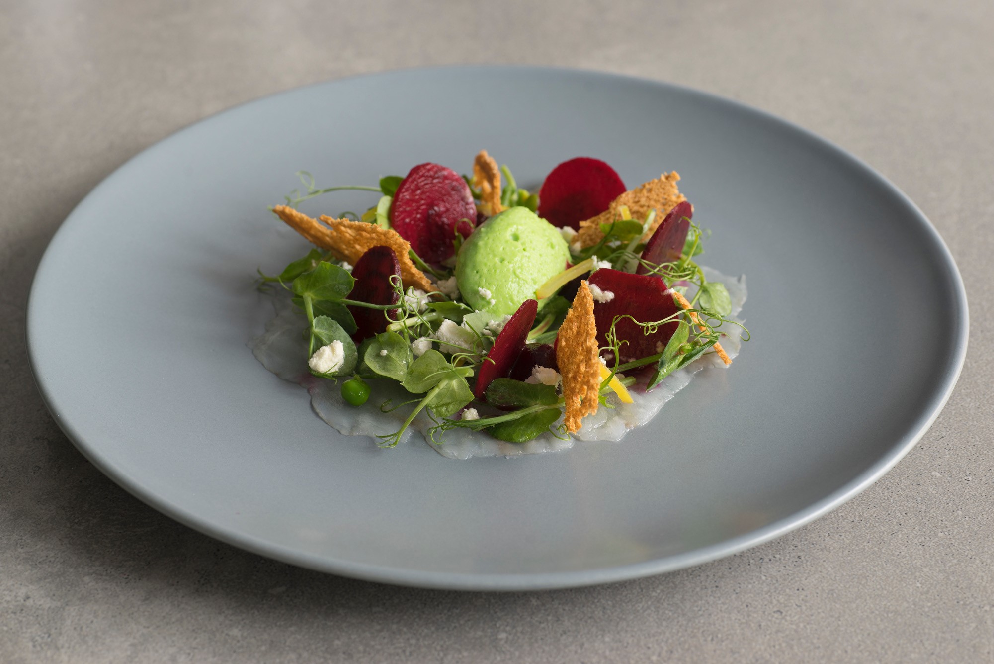 A green and purple seasonal dish on a grey plate at Bastion, Kinsale