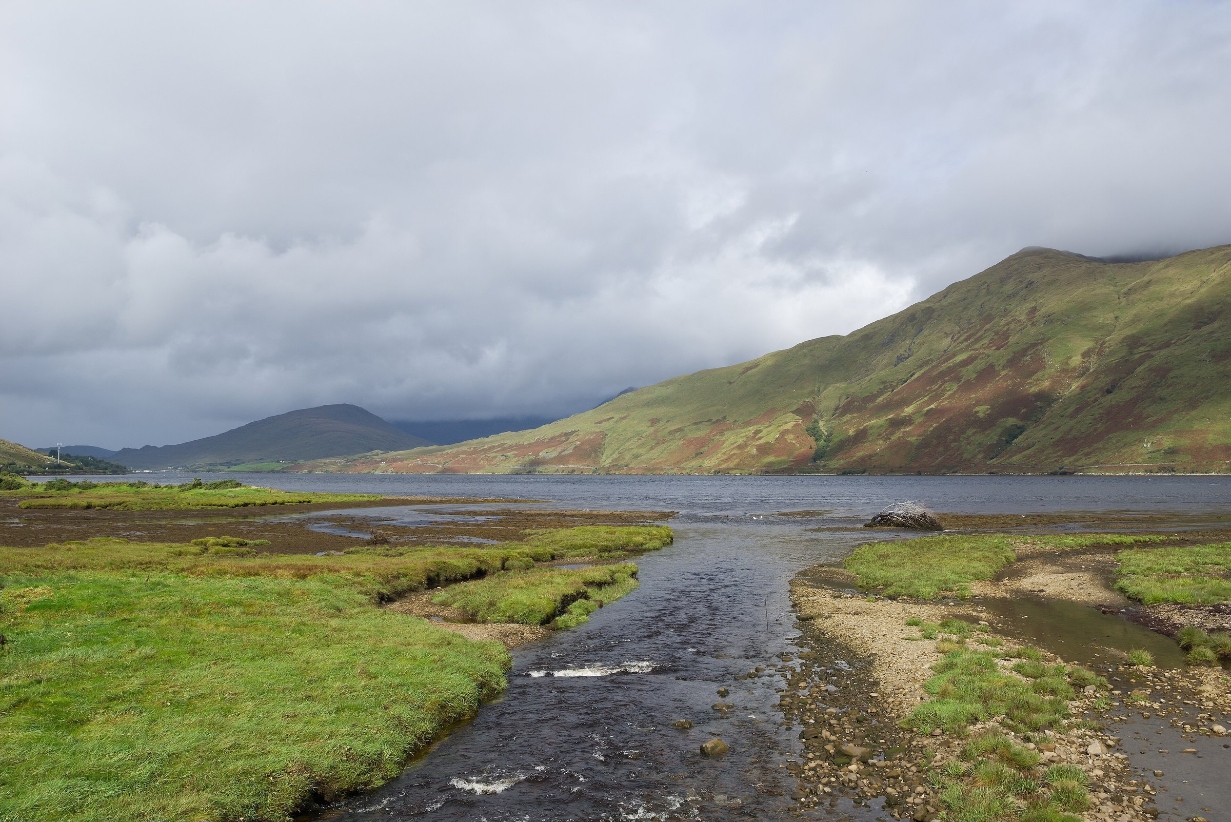 A stream entering Killary Harbour below cloud-covered mountains at Leenane